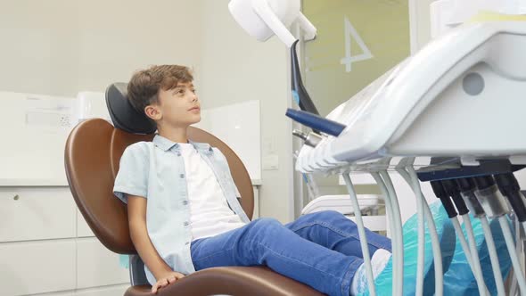 Lovely Young Boy Sitting in Dental Chair Waiting for Teeth Examination