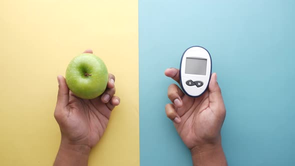 Holding Diabetic Measurement Tools and Apple on Table