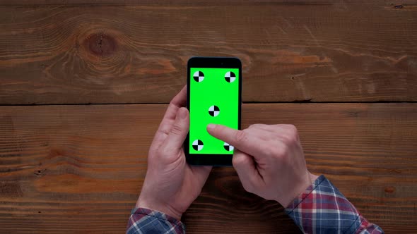 Man Using Smartphone  with Green Screen on Wood Table