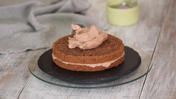 A Girl with a Spatula Spreading the Cream To the Chocolate Sponge Cake