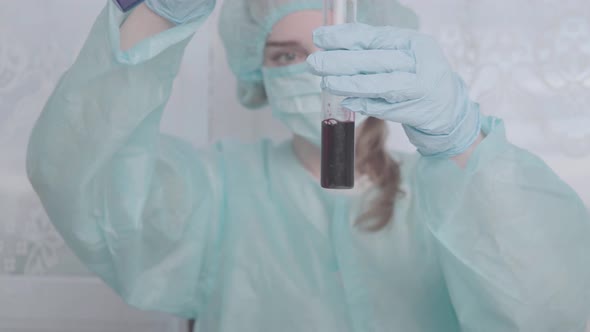 Doctor in protective gloves holds laboratory test tubes with liquid and mixes them