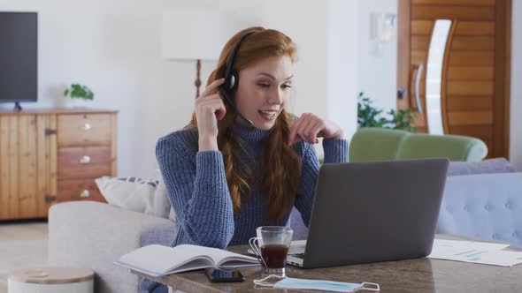 Woman wearing headphones using laptop at home
