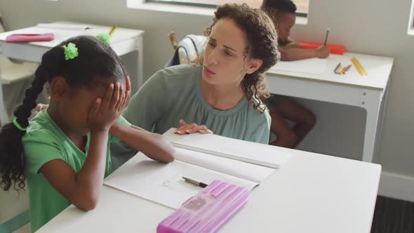 Video of caucasian female teacher supporting sad african american girl during lessons