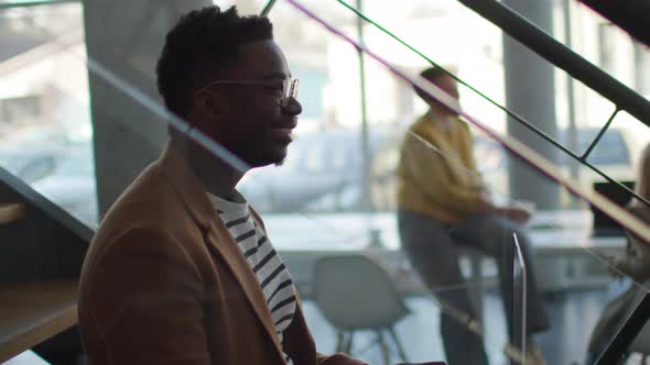 Handsome young African American business man on laptop while sitting at office stairs