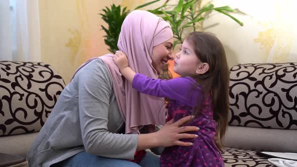 Happy muslim mother and little daughter. Loving mother in hijab hugs and kisses his smiling daughter