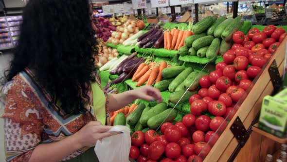 Young Woman Housewife in a Grocery Store Buys Takes Ripe Tomatoes From the Shelf and Puts Them in a