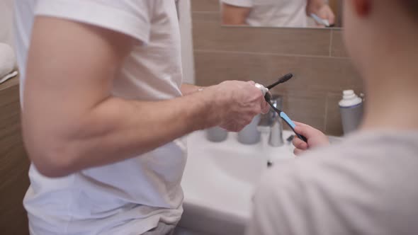 Father and Son Brushing Teeth Together