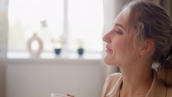 Woman Enjoys Cup of Hot Drink Relaxing in Office After Work