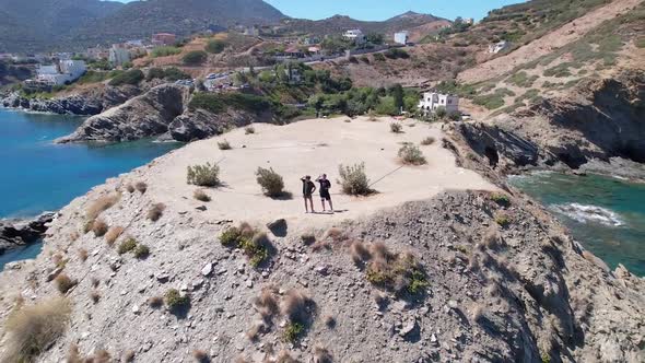 Drone flies over the rocky nature and blue sea with swimmers and boat in sight. Volcanic archipelago