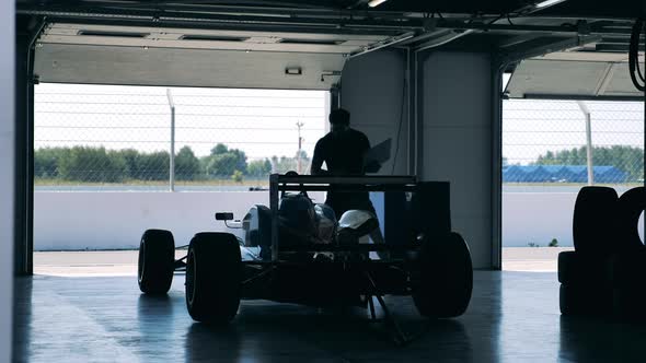 A Man with a Laptop is Inspecting a Racing Car