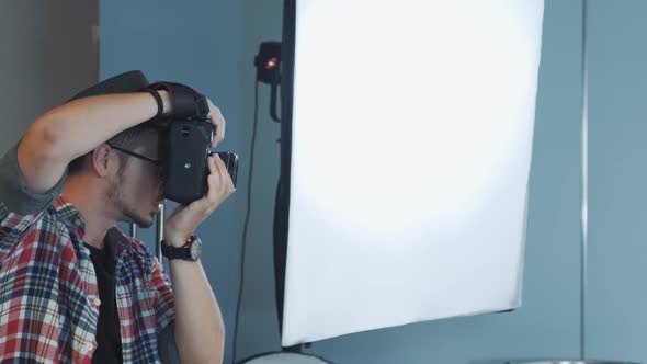 Profile View of Caucasian Photographer Working in Studio with Soft Box in the Background