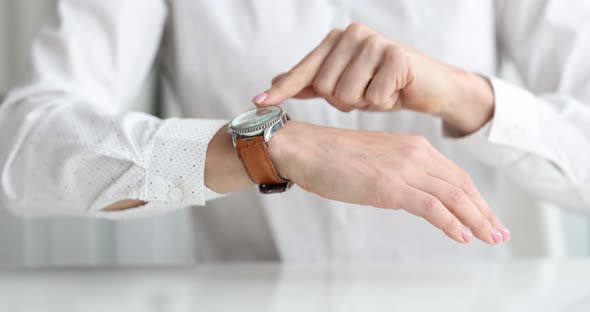 Businesswoman Points to Wristwatch on Hand Closeup