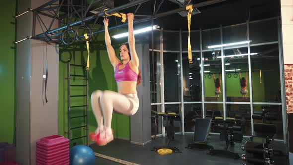 Beautiful woman doing exercises on abdominal muscles by lifting her legs in the gym.