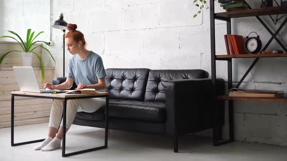 Redhead Young Business Woman Is Typing on Laptop and Working with Paper Document.