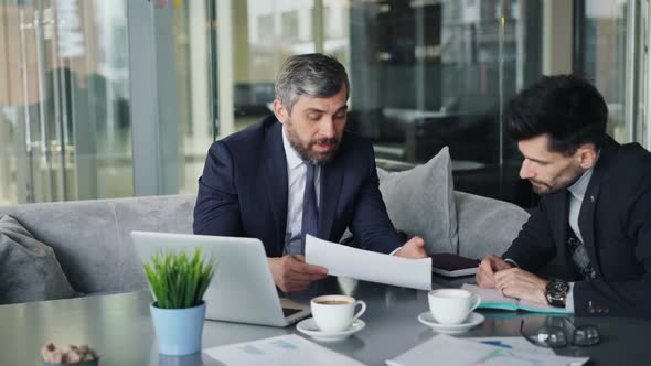 Angry Businessman Tearing Papers Throwing at Partner During Talks in Cafe