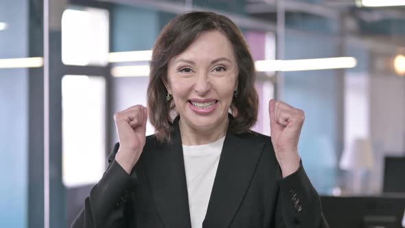 Portrait of Surprised Middle Aged Businesswoman Celebrating with Both Fist