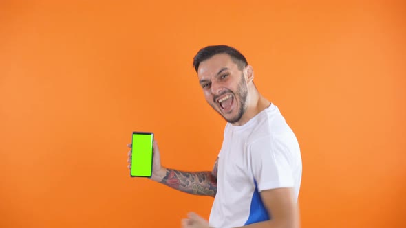 Happy Football Fan or Player Celebrating and Show Green Screen Phone