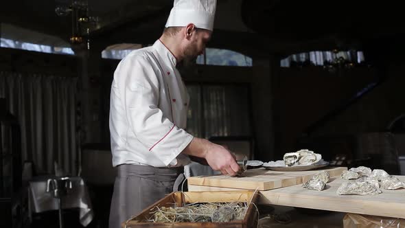 Chef in a Luxury Fish Restaurant Opens Oysters on the Table and Puts Them on a Plate with Ice