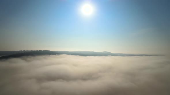 Aerial View of Colorful Sunrise Over White Dense Fog with Distant Dark Silhouettes of Mountain Hills