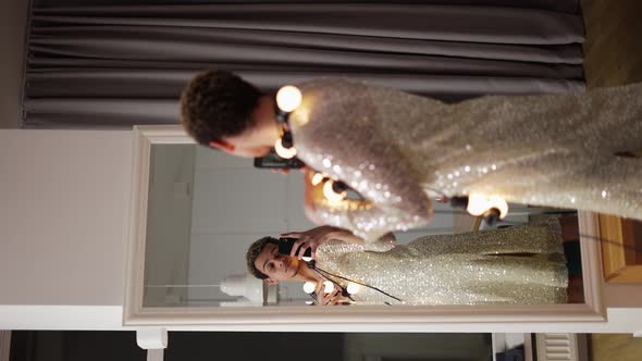 A Man in a Dress Posing in Front the Mirror with Garland on Neck Sensually Moves