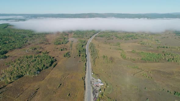 Aerial Panoramic View of an Intercity Road Between Green Fields and Trees with White Fog Clouds Over