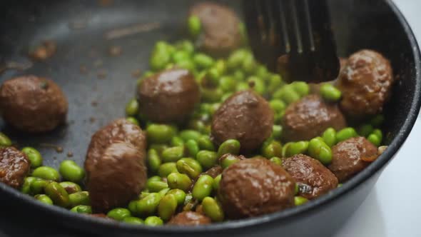 Unrecognizable person cooking green beans and meatballs