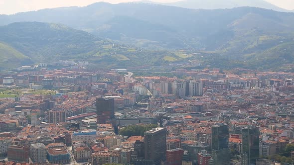 Scenery overlooking big city on hot summer day with mountains at back, panorama