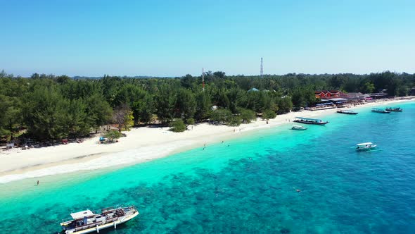 Traditional boats anchoring on tranquil turquoise lagoon near shoreline of tropical island with gree