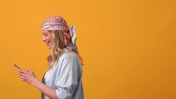 Positive blonde woman hippie texting by phone