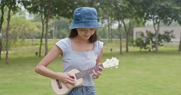 Woman enjoy play ukulele at outdoor