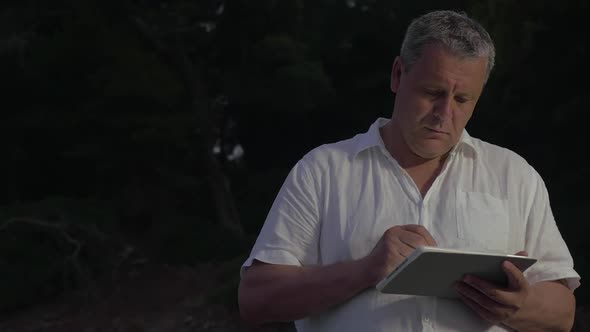 Man Typing in Tablet in Twilight