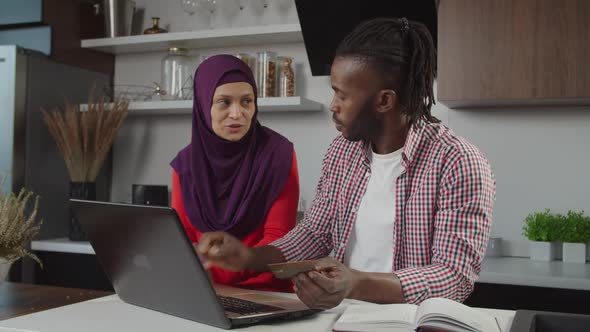 Positive Multiracial Couple Making Online Shopping Together Using Laptop Pc Indoors