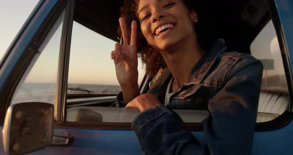 Woman showing victory sign in pickup truck at beach 4k