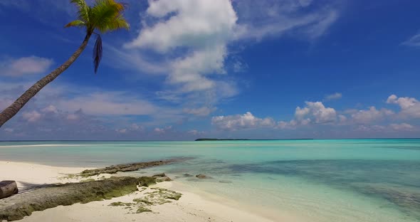 Wide fly over copy space shot of a sandy white paradise beach and blue ocean background in vibrant 4