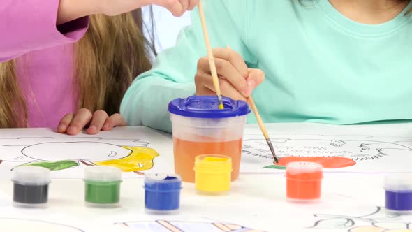 Small Children with the Help of Brushes and Paints Decorate Drawings, They Like It. Close Up. White alt