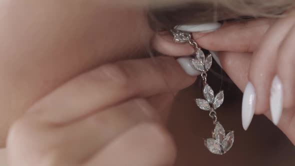 Woman with White Manicure Puts Silver Floral Style Earring