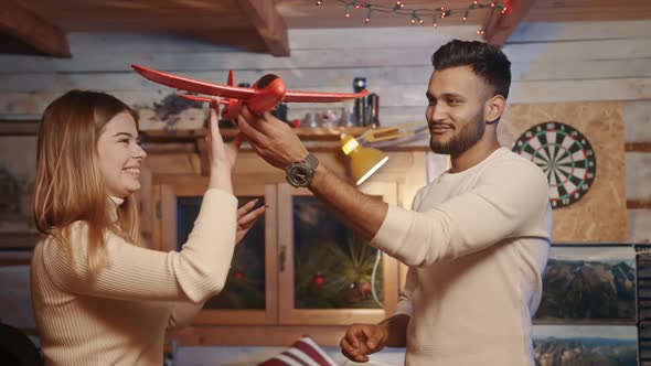 Happy Young Couple Playing with Red Airplane Toy