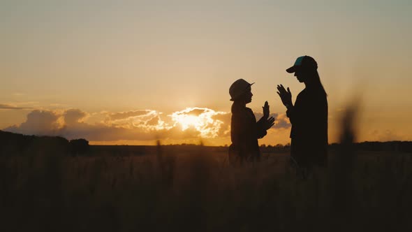 Silhouette Happy Mothers and Daughters Playing in a Wheat Field at Sunset. Concept of Friendly