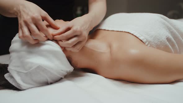 Woman Receiving Facial Massage in Spa Lying on Massage Table. Wellness Body and Skin Care