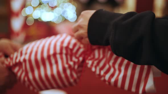 Close Up of Young Girls Hands Making Knot on Big Candy Gift Box of Candy Among