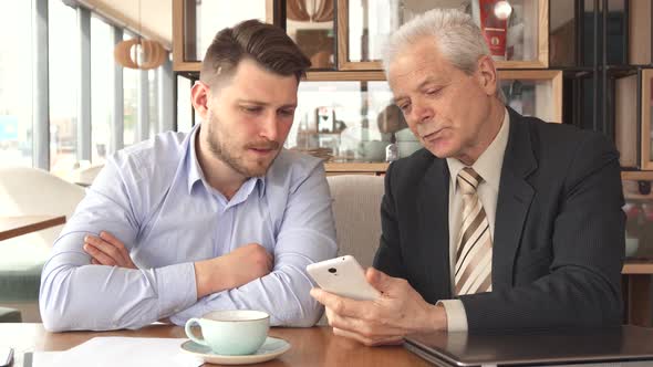 Senior Businessman Shows His Partner Something on His Smartphone