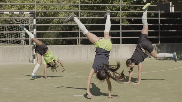 Long Shot of Happy Women Doing Cartwheel at Football Stadium