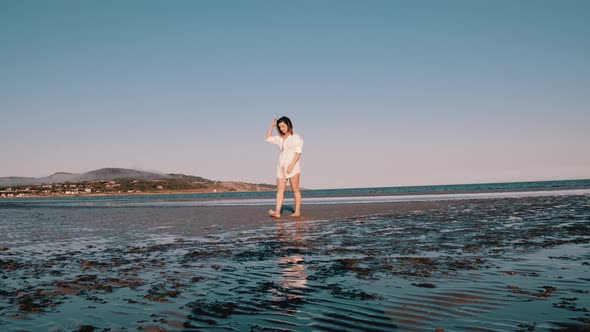 A woman walks barefoot on the beach