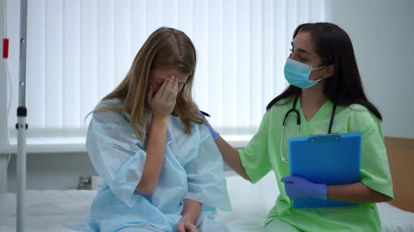 Teenage Girl Crying Sitting on Bed with Doctor Touching Shoulder Endorsing Patient