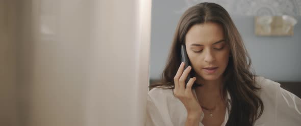 Close up of a woman talking to someone on the phone, near the window