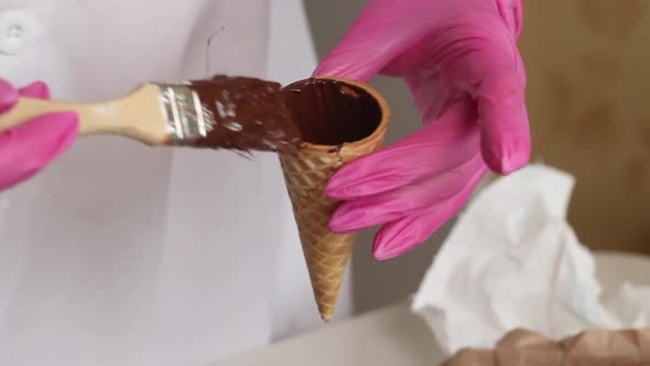 A Woman Smears Waffle Cones With Liquid Chocolate. Makes Horns With Chocolate And Marshmallows.