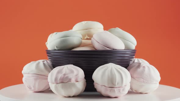 Close-up of Coloured Marshmallows It Plate Rotation Over Orange Background