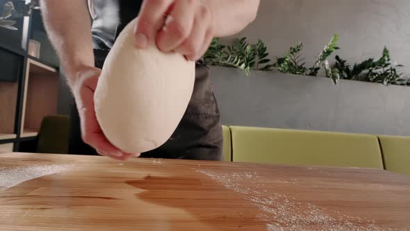 Man Baker Kneads Dough for Baking and Bread on Wooden Table