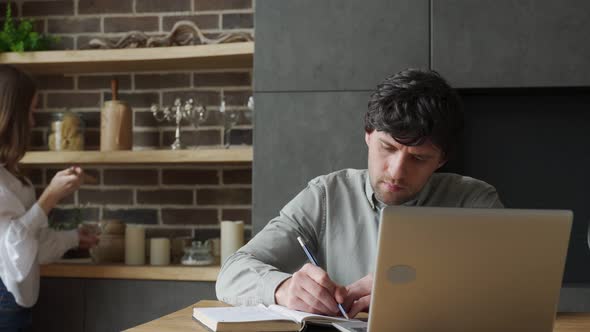 Young Couple Working in Kitchen with Laptop