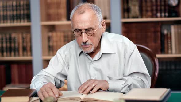 70s Grandfather Teacher Professor Scientist Reading Ancient Paper Book Sitting at Public Library